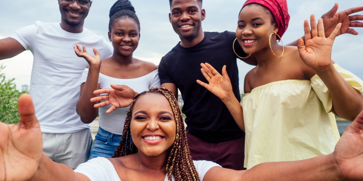 group of five friends female and male taking selfie on camera smartphone and having fun outdoors lifestyle near lake